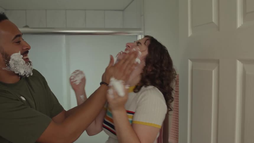 A couple plays with shaving foam in a bathroom