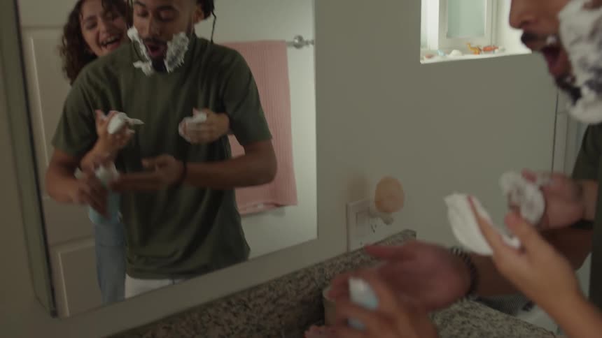Man and woman put shaving foam on one anothers face in the bathroom