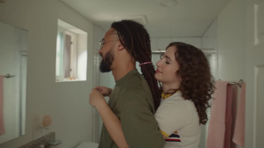 A man and a woman in the bathroom playing in front of the mirror using their hands and bodies
