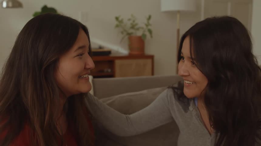 Two women talking while sitting on the couch indoor