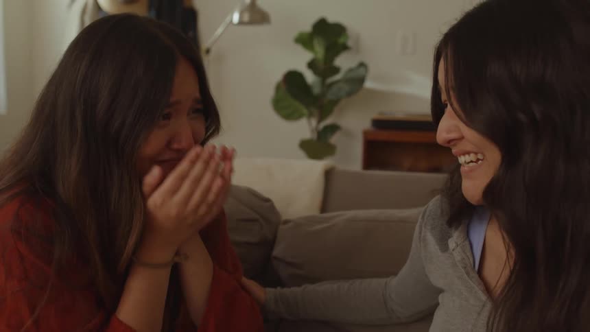 Woman consoles her friend crying and sitting on the couch in the living room