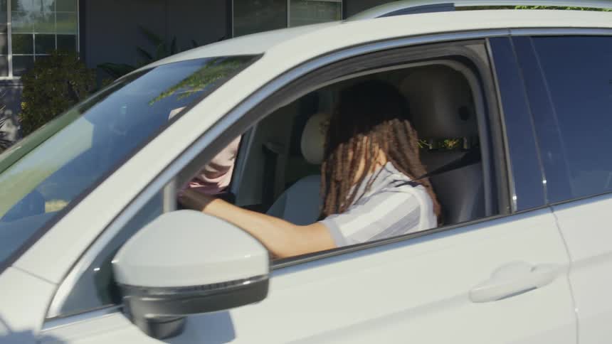 People in a car parked in front of a gray house