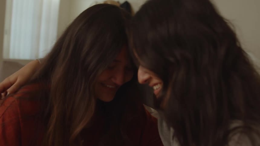 Two friends sitting and smiling giving each other a hug