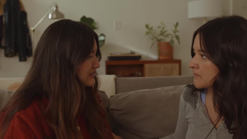 Two women sit on couch one comforts the other