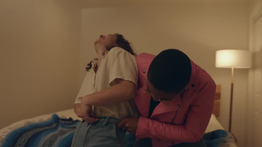 Two women laugh while trying to put on jeans
