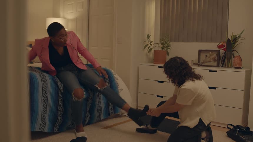 Friends in a room are trying to take off their shoes
