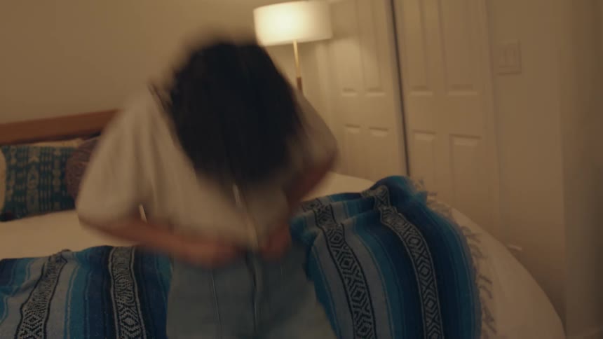 A teenager struggles to close the zipper on her pants while her friend cheers her on and when she succeeds by falling back on a bed they both celebrate