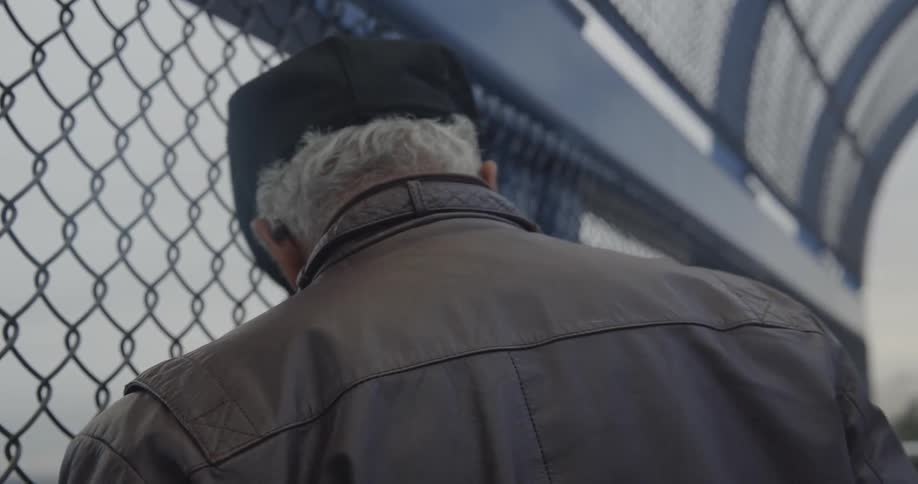 A man leans against a fence and walks off
