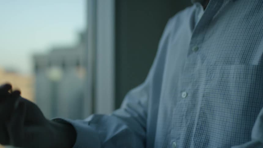 A man is buttoning up his shirt