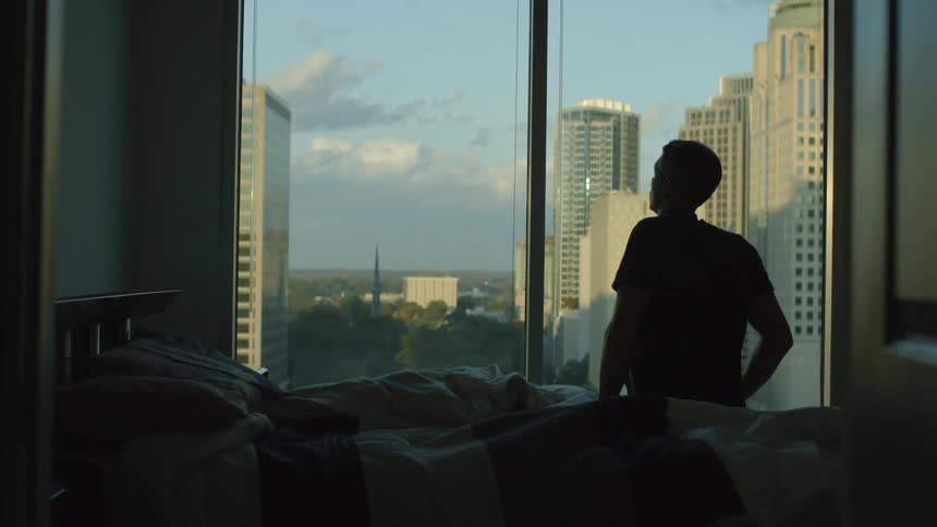 Man looks out the window at a large city