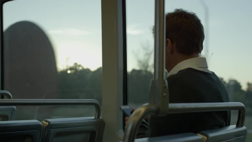 A man is riding a train at sunset
