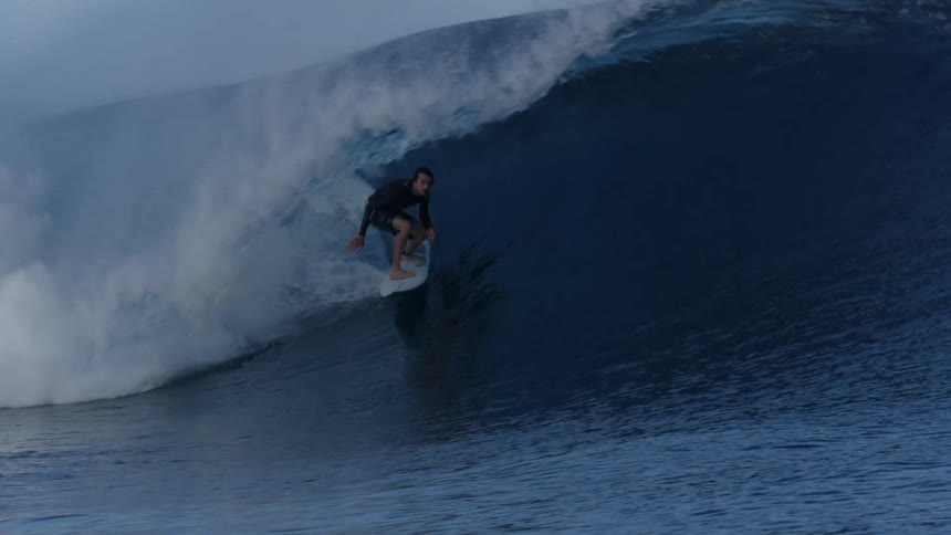 A man in his swim wear riding the sea waves on his surfing board