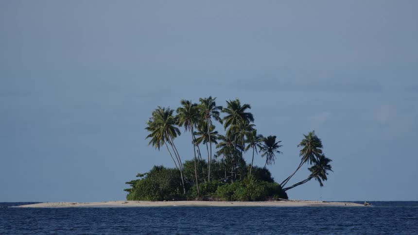 View of a small island with sand and the sea with waves around it