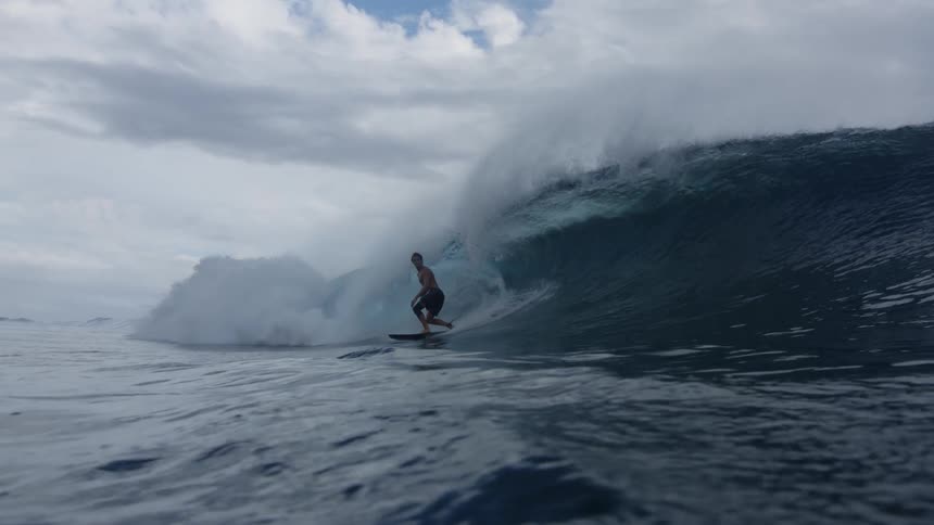 Man surfing outdoors at the sea near a beach next to a mountain range during day time