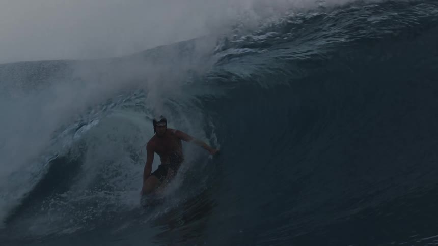 Man rides a wave with a surfboard at morning