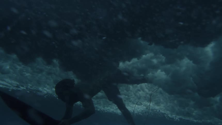 A surfer dives under the wave with a surfboard