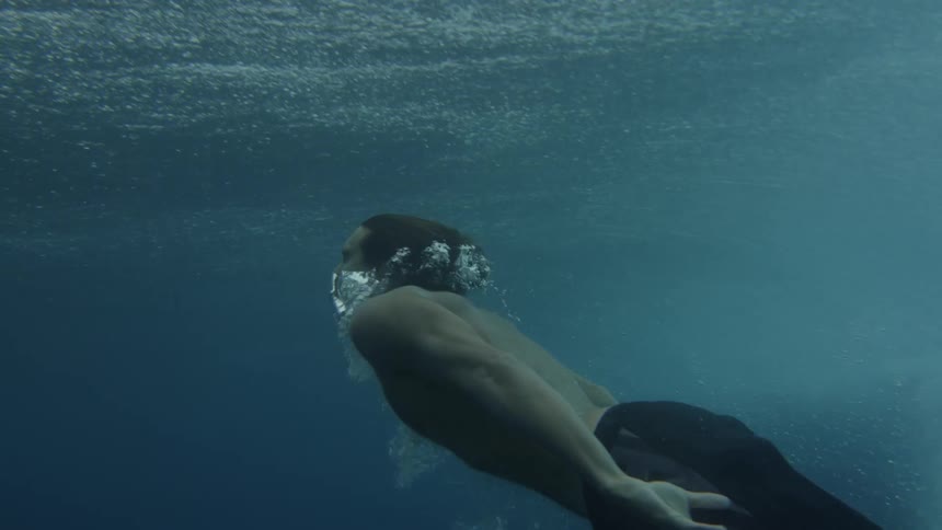 Man swimming underwater in a blue ocean