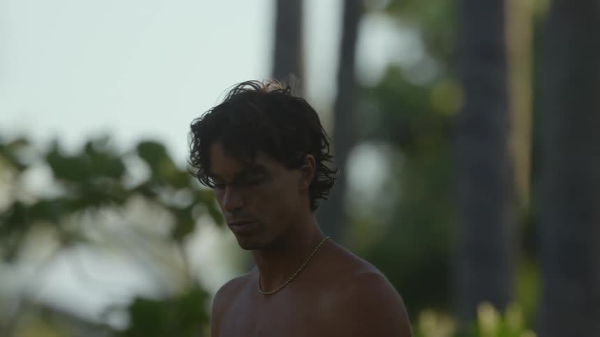 Portrait of a young man holding his surfboard in the midst of nature