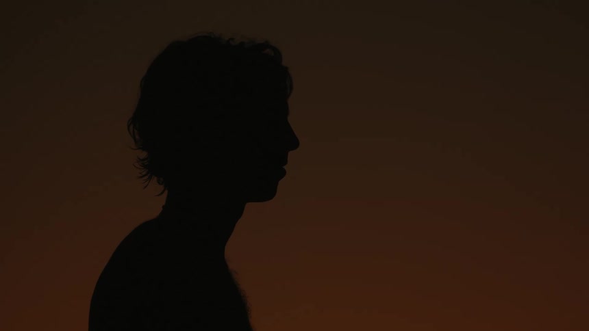 Silhouette of a man holding a surfboard at sunset