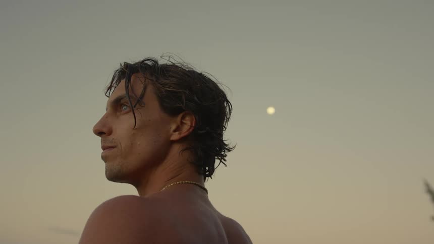 Young man on a beach turns his head around