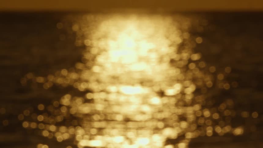 Gold sunlight reflecting on the surface of the ocean at evening