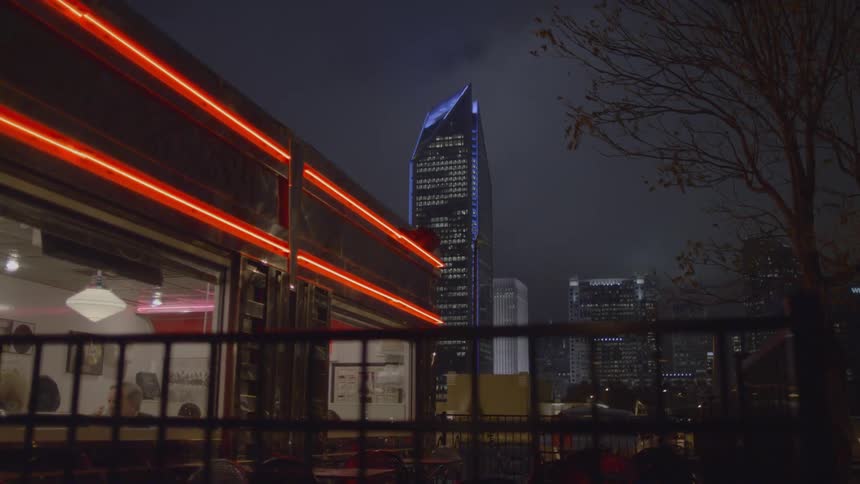 Red neon lights shine above the large windows of a diner at night