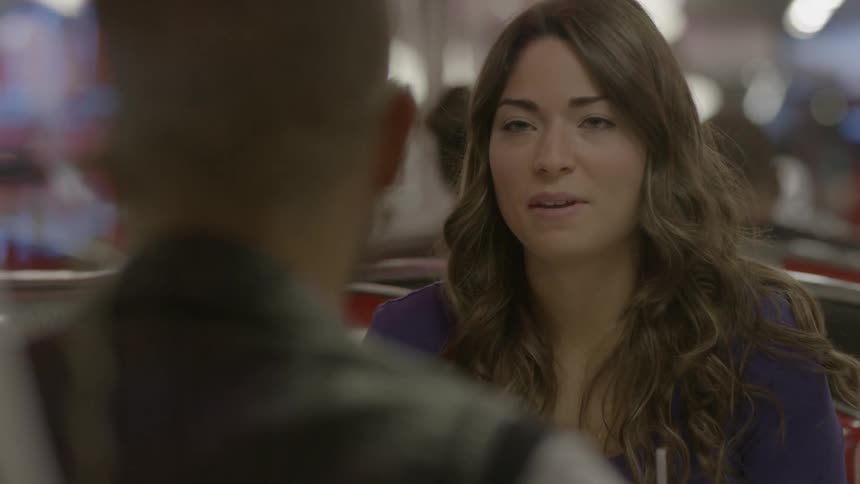 A woman is talking as she sits with a man in a restaurant