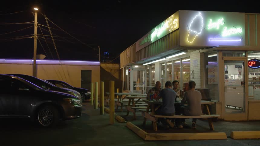 People sit outside and eat by a ice cream shop
