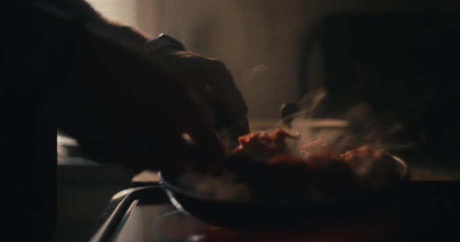 Hands of a person cooking food in a pot on the stove