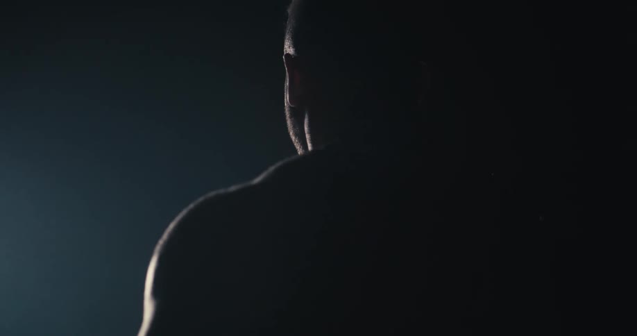 View of a shirtless man in a dark environment