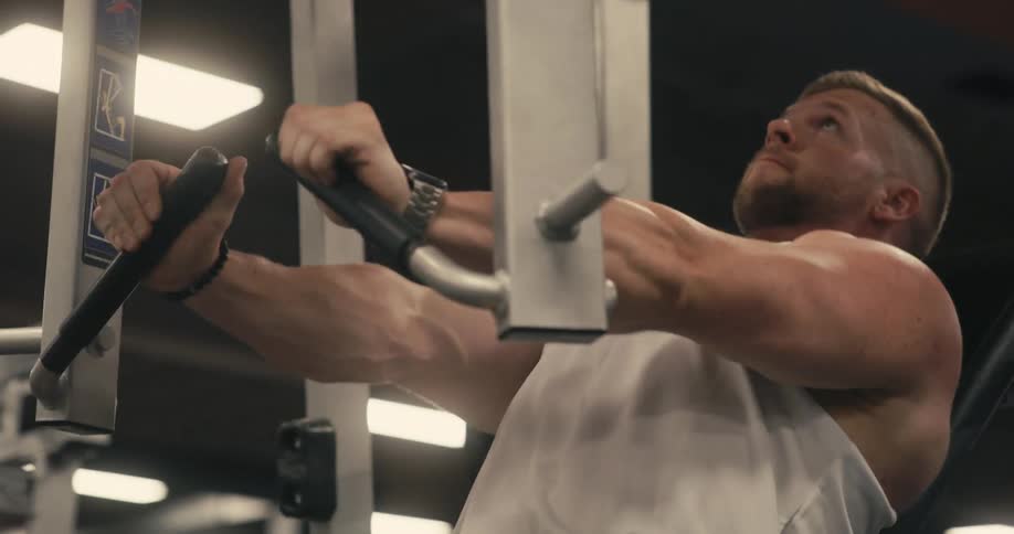 Man works out in gym using weight machine