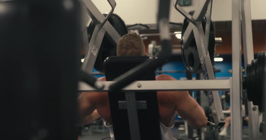 Man in the gym training his arms on a machine