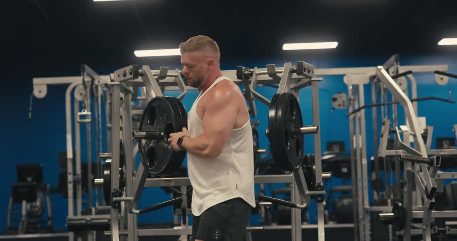 A muscular man lifts himself off a weightlifting machine at a gym