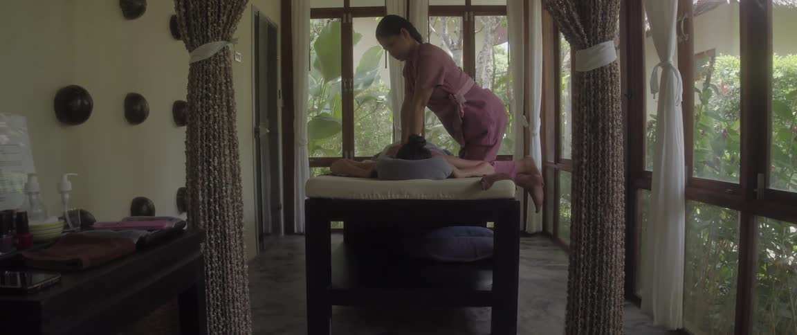 Woman giving a back massage to another woman in an indoor setting