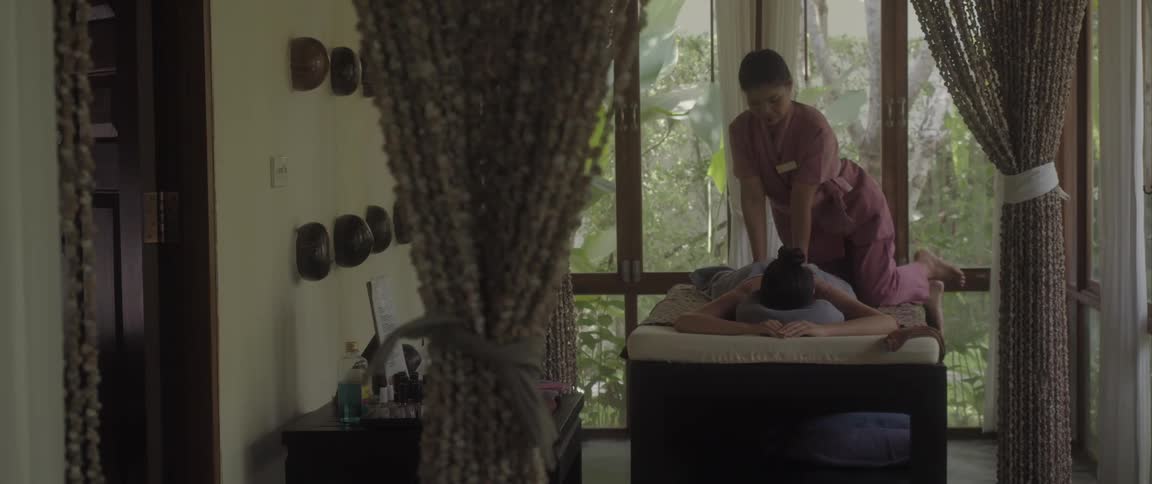 A woman is kneeling over a person lying on their stomach as she gives them a massage
