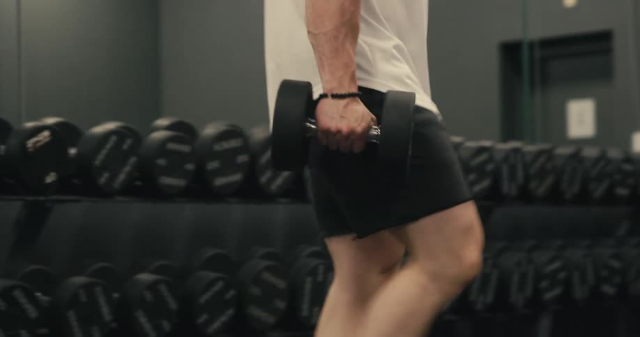 Man at the gym picking up weights and sitting on a bench