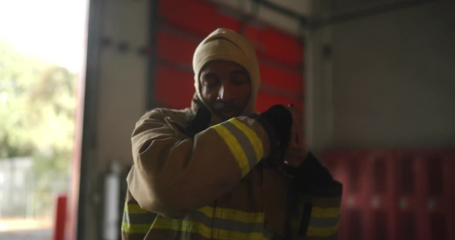 A firefighter is dressing and zipping up his jacket