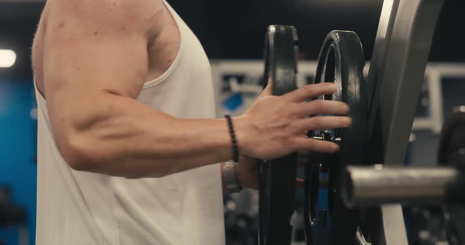 Man putting weight plates on a barbell at the gym