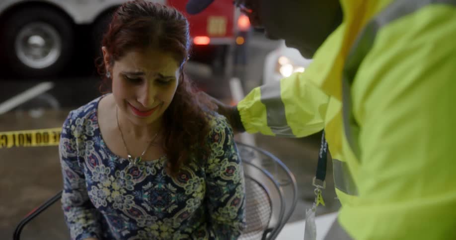 Woman sitting crying being comforted by a firefighter