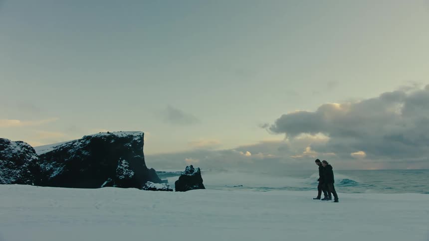 Two men were walking on the snowy beach at sunset