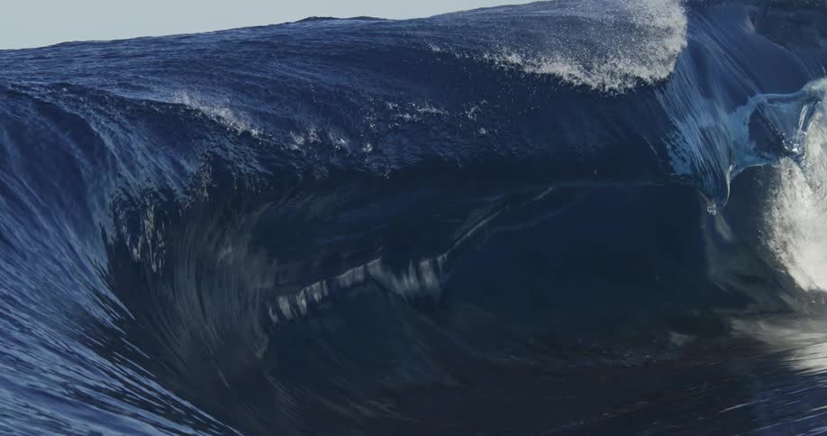 Wave rolls and crests across ocean surface