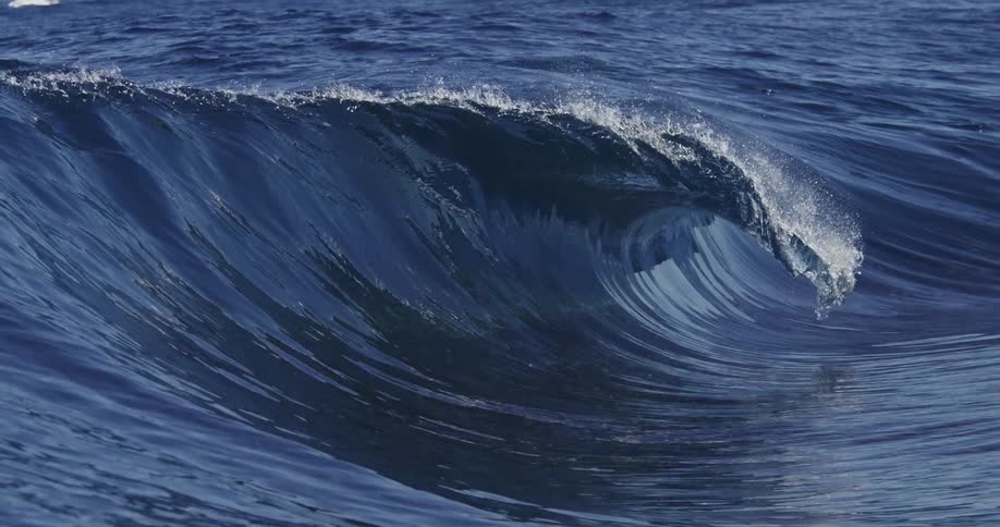 Ocean waves rolling and crashing onto the waters surface in the middle of the day