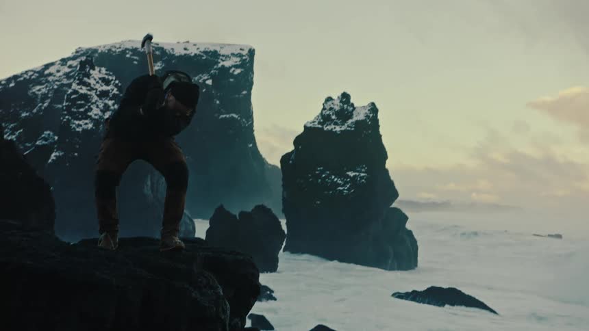 Man hammering a rock by the sea