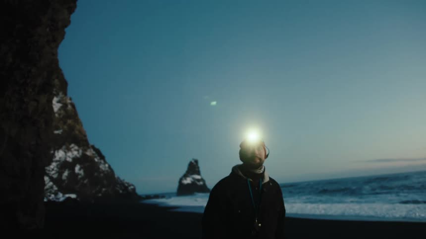 Man enters cave on beach during winter after dusk