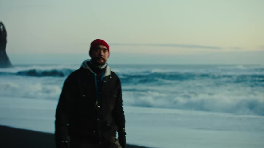 A man walks on the beach watching the scenery at sunset