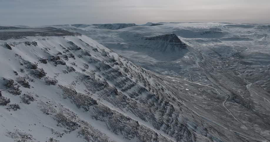 Drone view of a wide landscape covered in mountains and snow with valleys