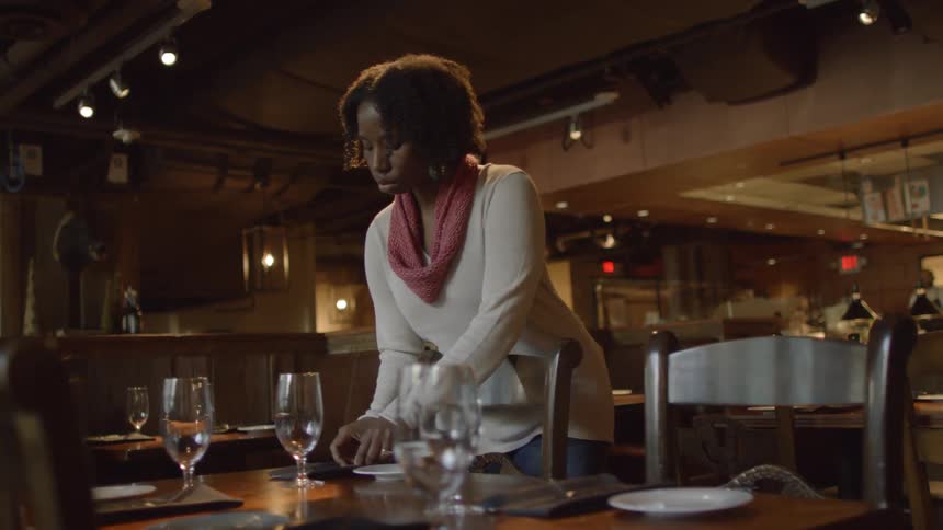 Woman sets a table at a restaurant