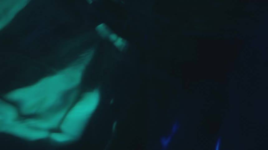 Shapes of turquoise and electric blue lights are moving in the darkness