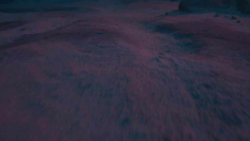 Rocky land with ridges along the surface with an orange bright light on the horizon