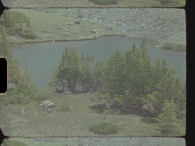 A small lake with trees and mountains of stones on a sunny day